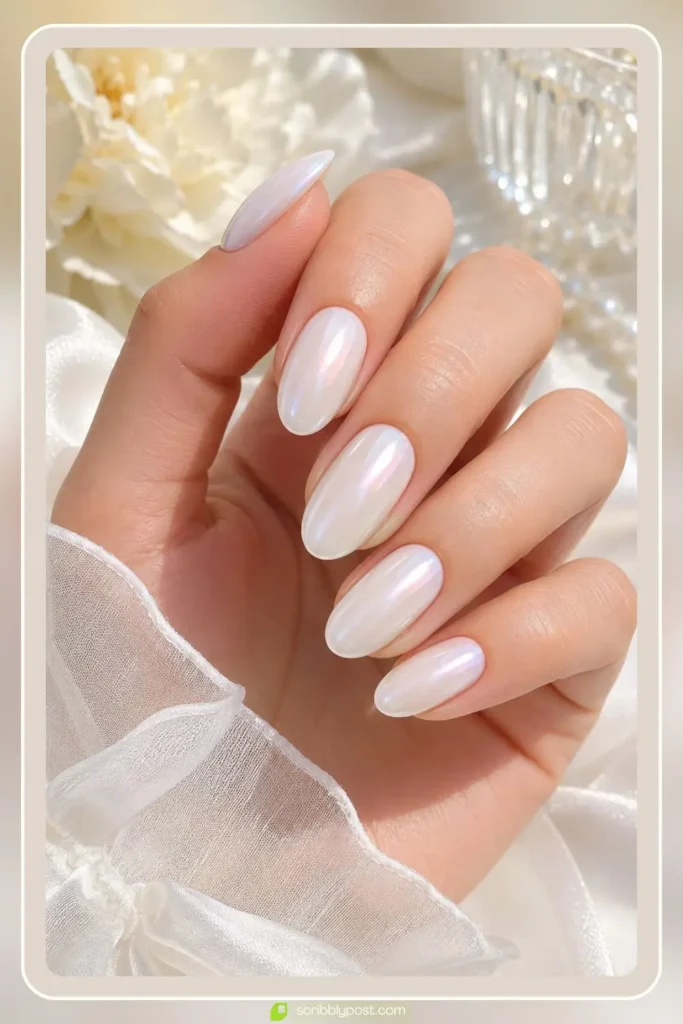 Oval pearl white nails with soft iridescent finish styled with gold rings
