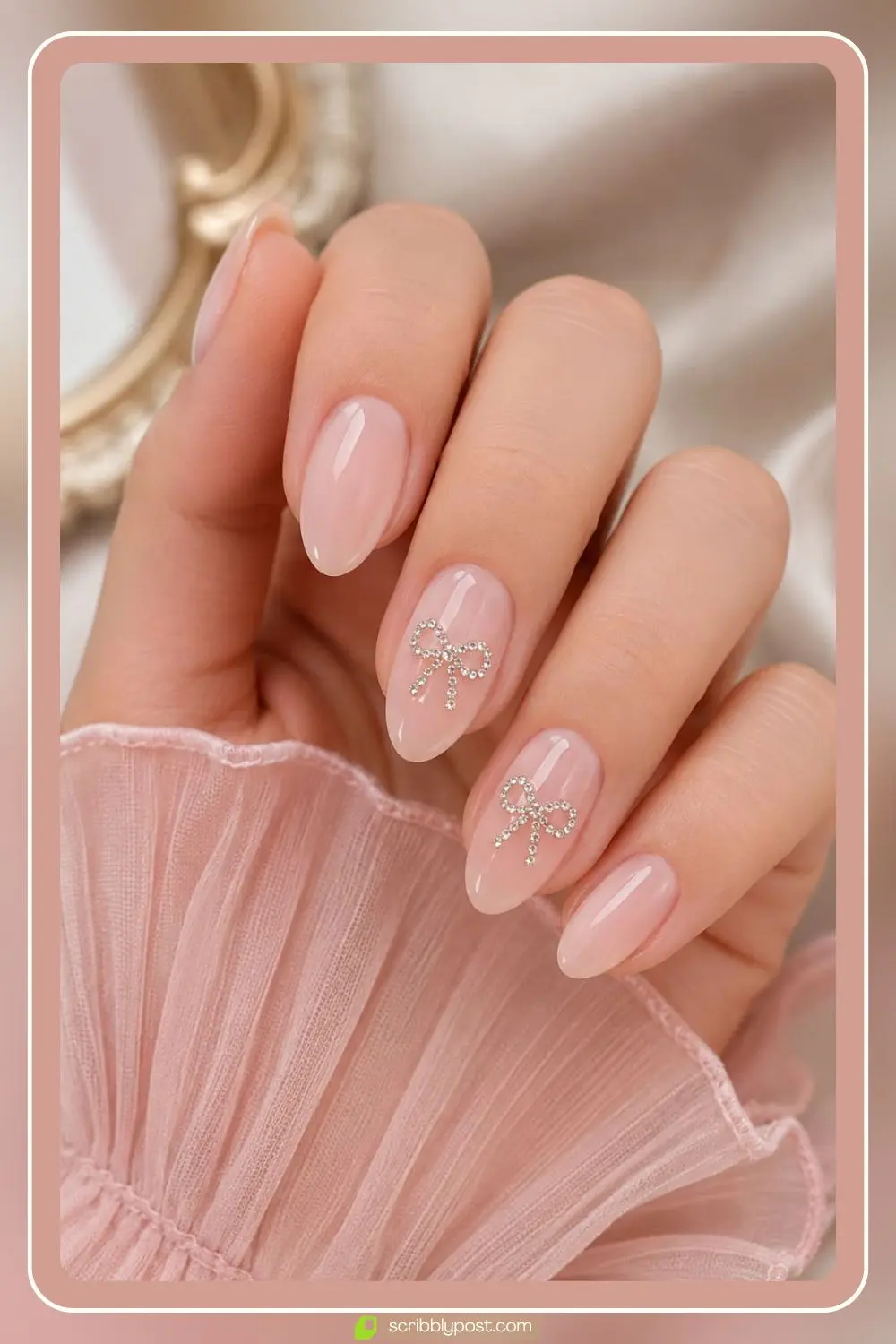 Milky pink nails with rhinestone bows centered on accent nails