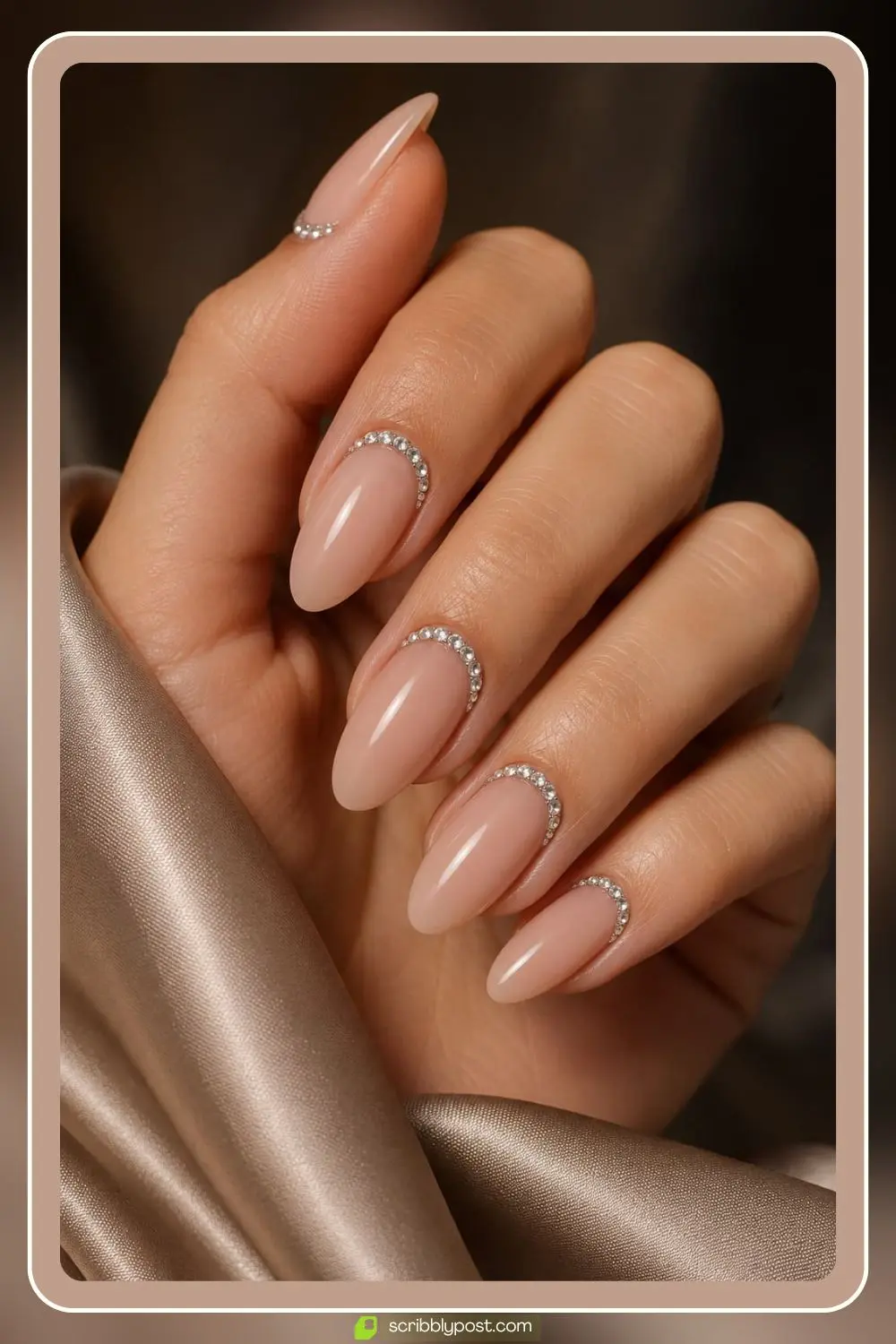 Nude nails with rhinestones arranged in crescent moons around the cuticle line