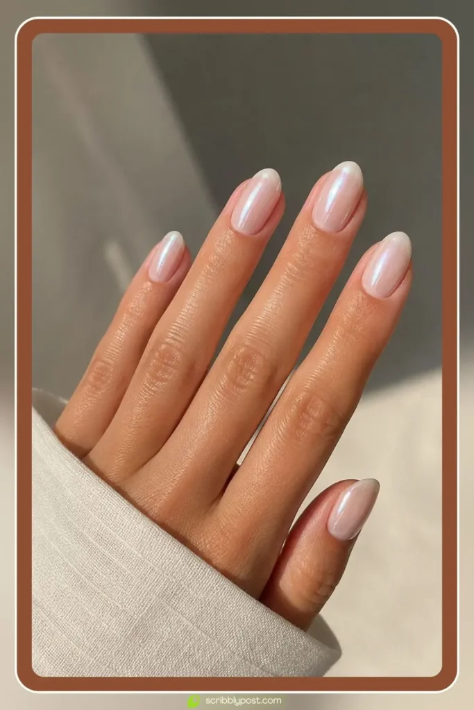 Short almond nails with milky base and soft pearl chrome shine in sunlight