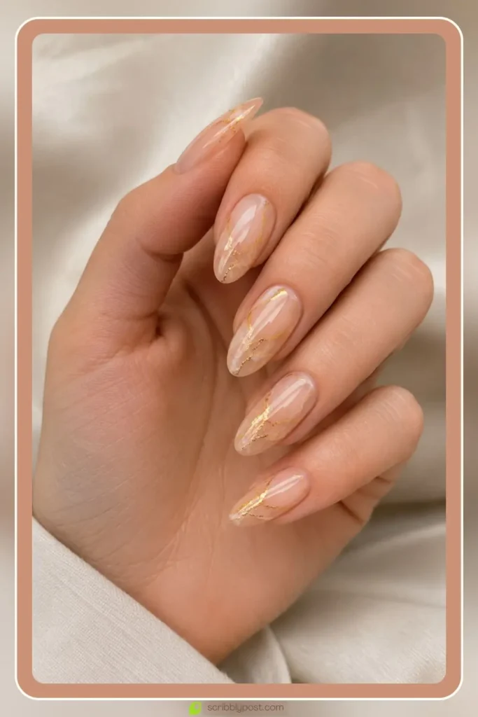 Gold veined nude marble nails on oval shape with sheer nude base and fine gold leaf veining