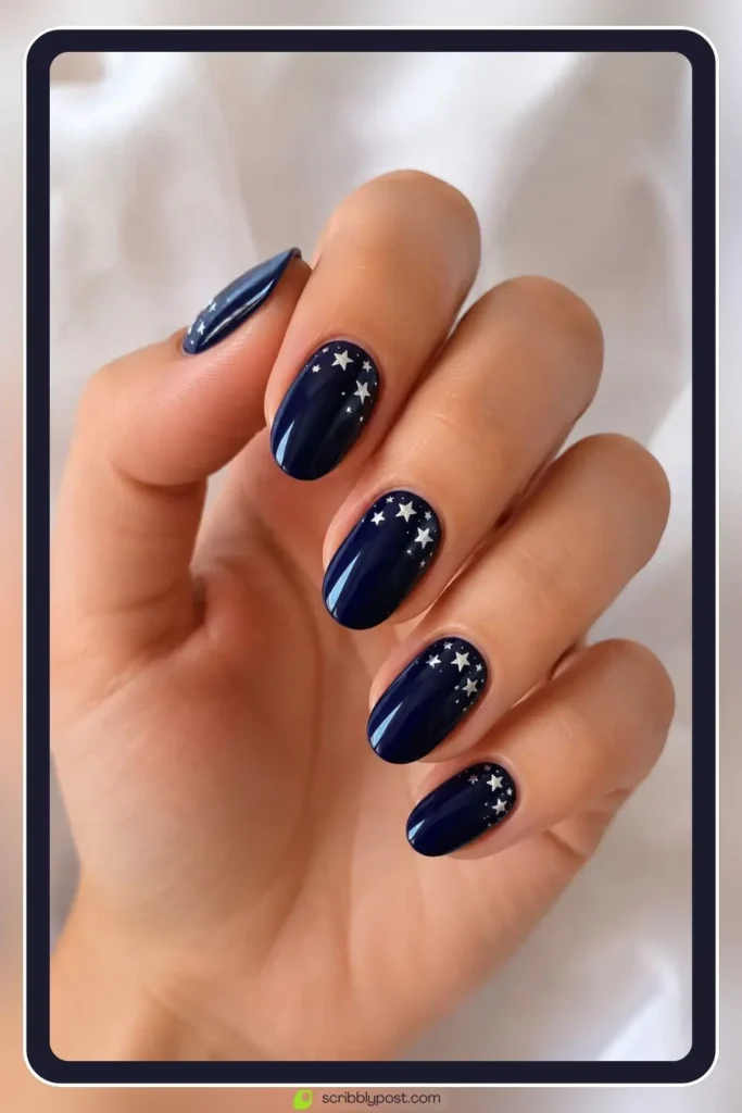 deep navy nails with scattered white star studs near cuticle on medium length