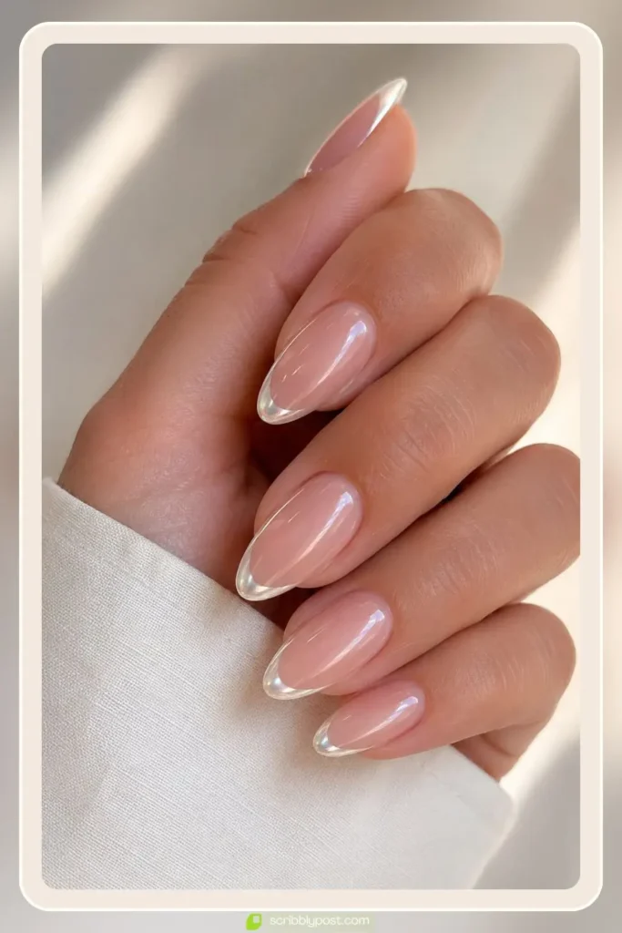 Almond nails with sheer pink base and pearl chrome french tips catching the light