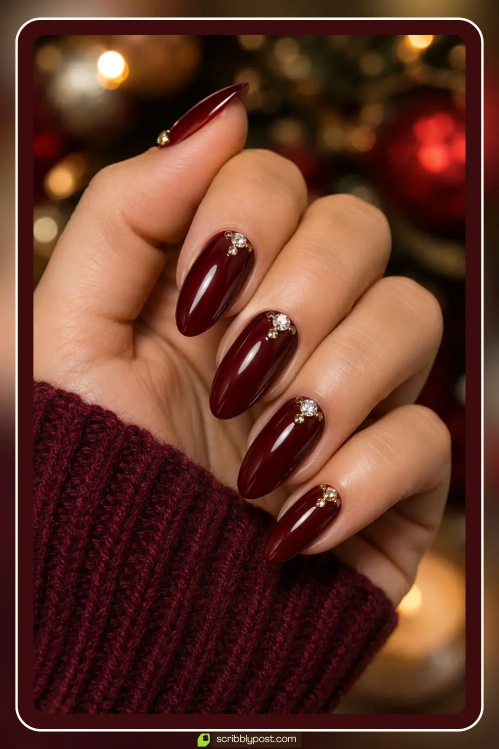Deep red nails with gold and clear rhinestone accents for a holiday look