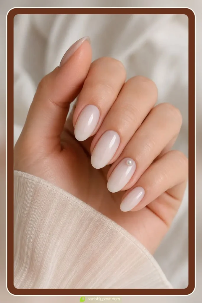 Single pearl accent nail with flatback nail pearls on a milky white clean girl base