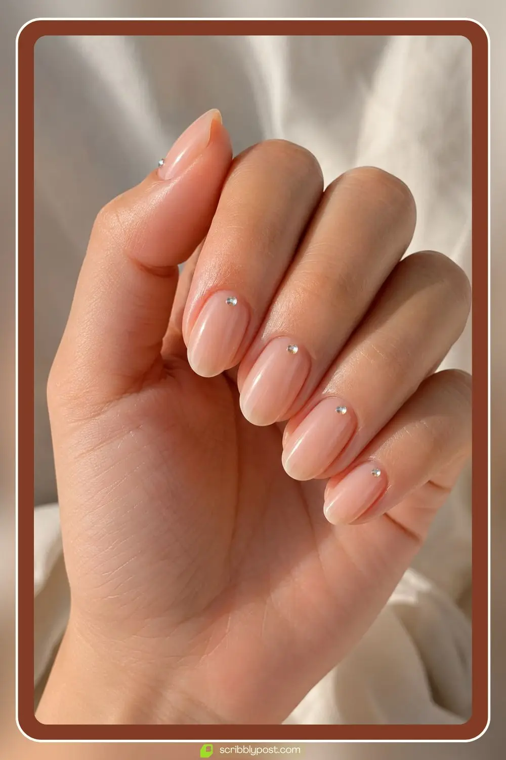 Nude nails with a single small rhinestone placed at the cuticle of each nail