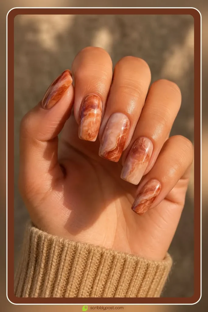 Terracotta rust marble nails on oval shape with cream veining on a warm rust base
