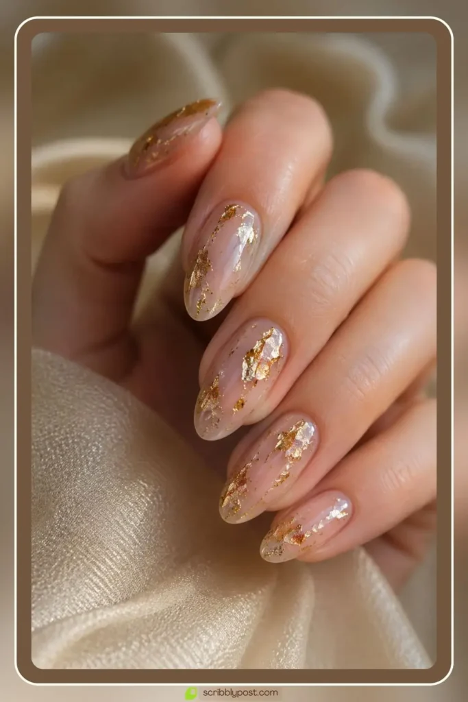 Gold foil flakes scattered on sheer nude nails