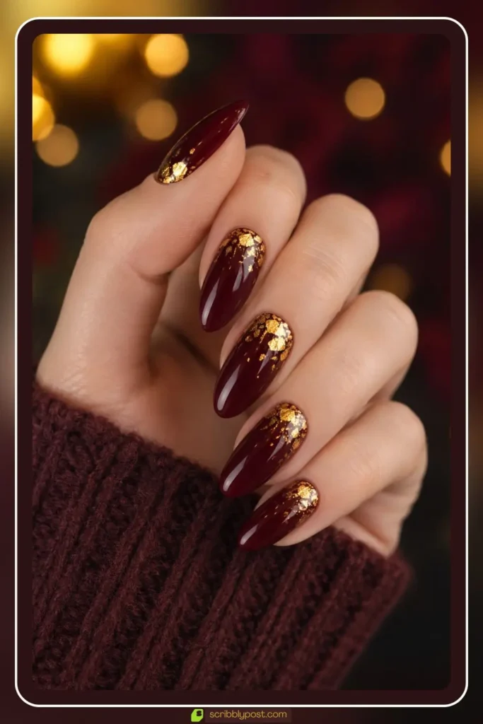 Burgundy nails with gold foil flakes scattered on glossy base