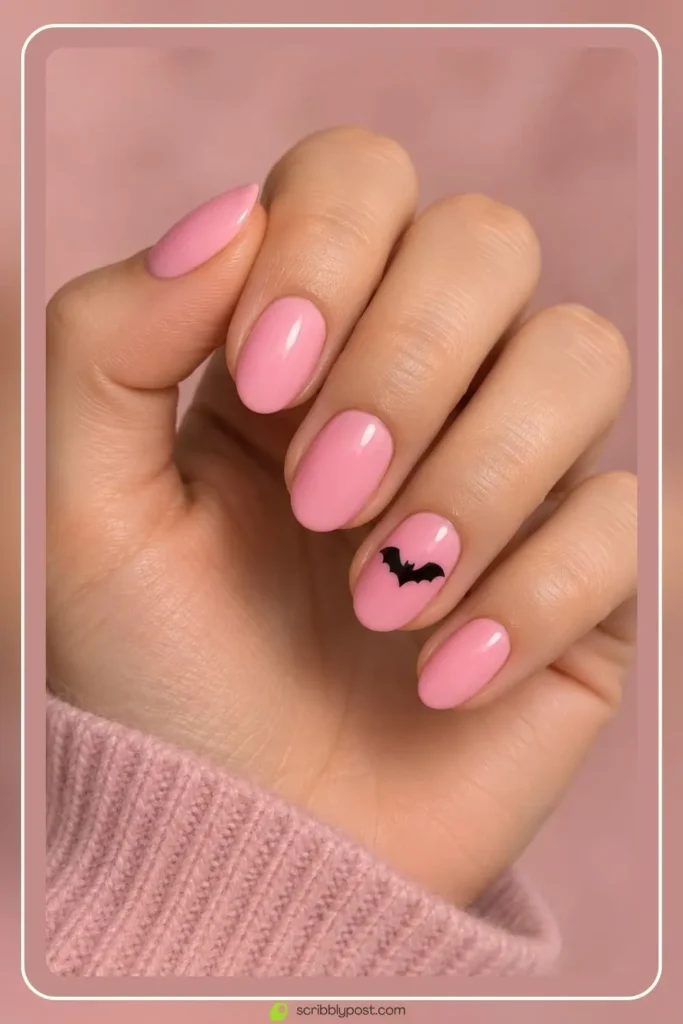 The Halloween Nail Scale: Five Levels from Nobody Would Know to Full Spooky 8 Pink halloween nails with a small black bat silhouette on one short nail